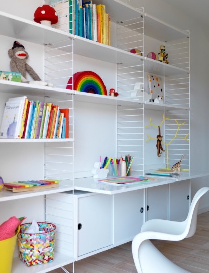 Système d'étagères String blanc avec bureau intégré et caissons, installé dans une chambre d'enfant